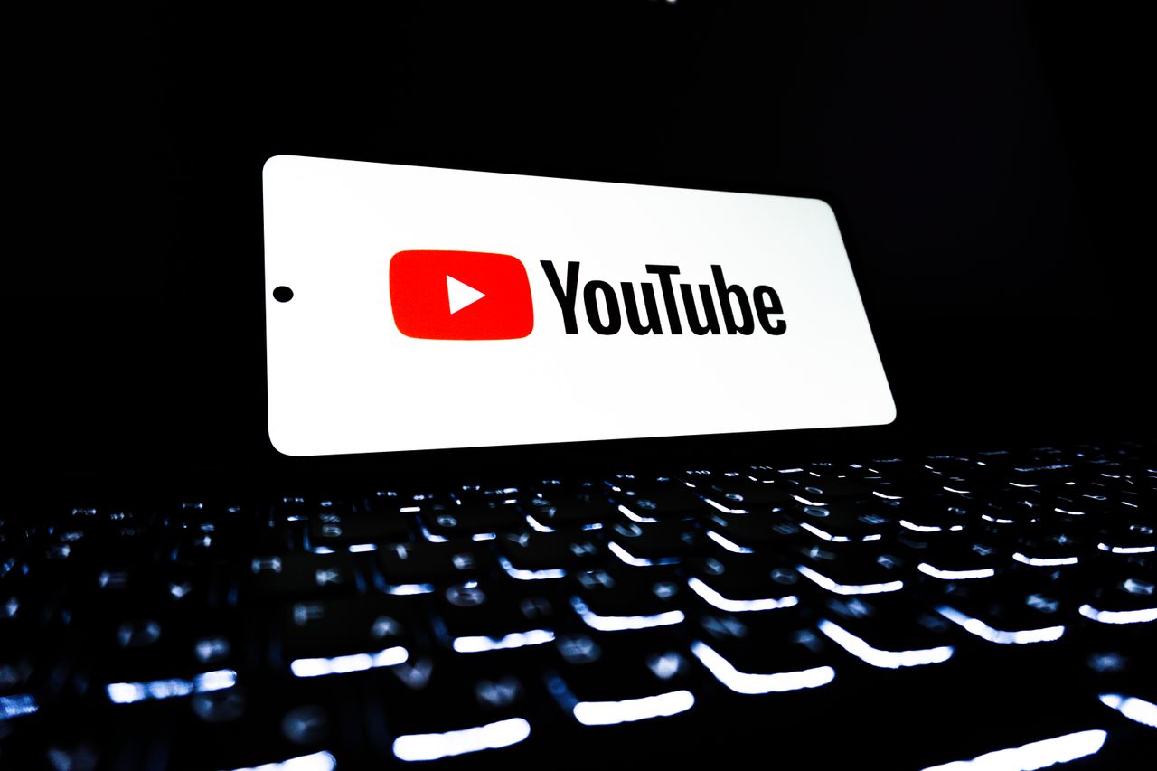 about-us-01 YouTube app icon displayed on a smartphone over an illuminated keyboard, representing digital media and online streaming.